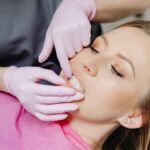 A Person Wearing Latex Gloves Checking a Woman's Teeth